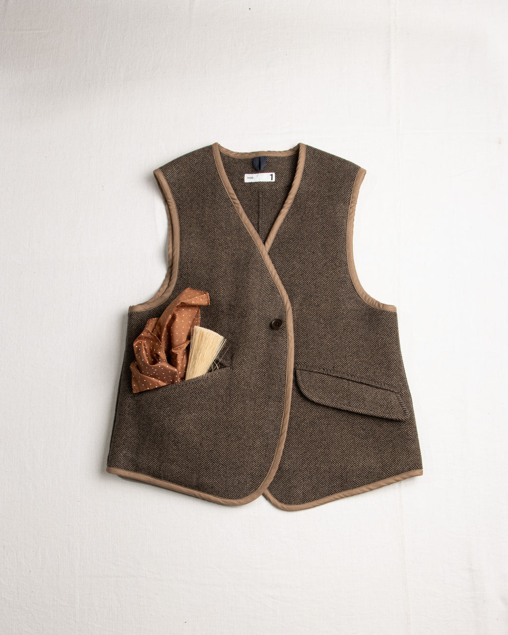 Herringbone Wool Vest with a backslit in warm brown color. it has a single button closure and functional pockets.