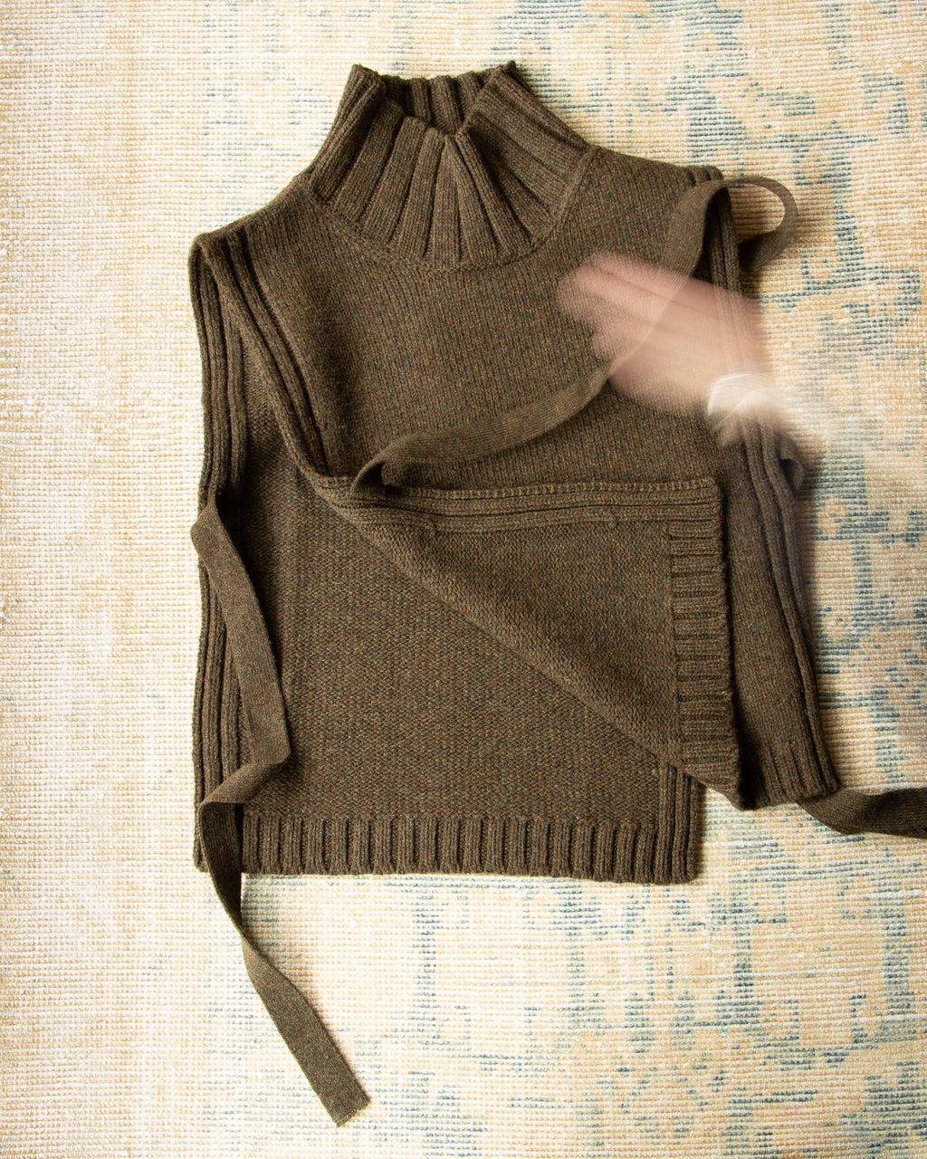 Brown knitted khaki vest on a textured surface