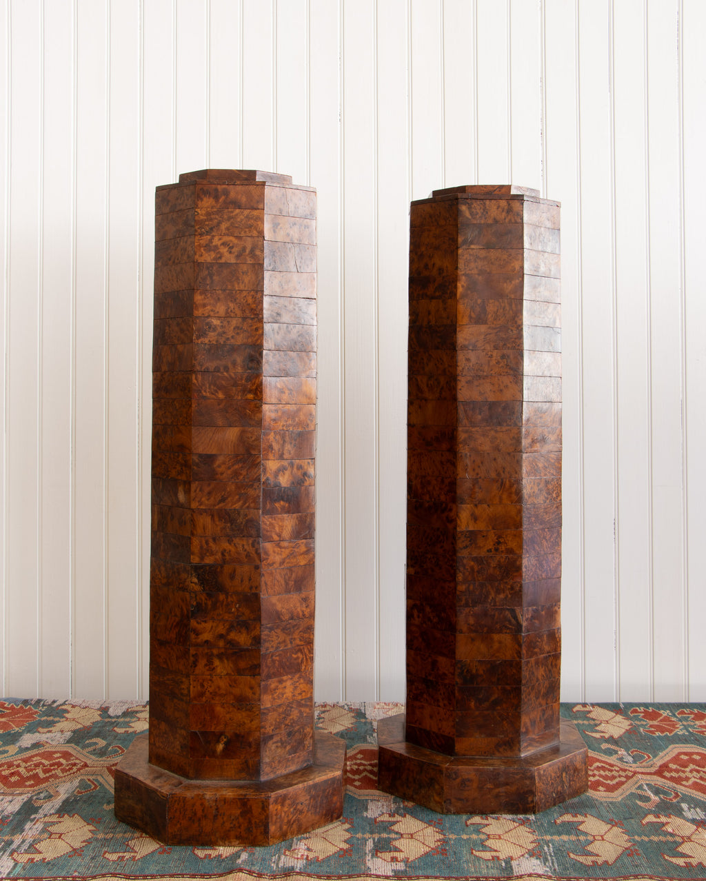 Two hexagonal wooden columns against a white paneled wall.